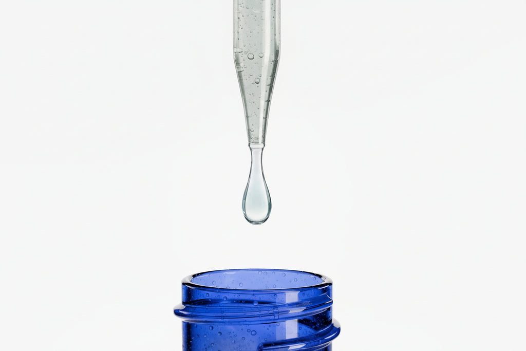 Blue glass container with a dropper dripping liquid onto a white background